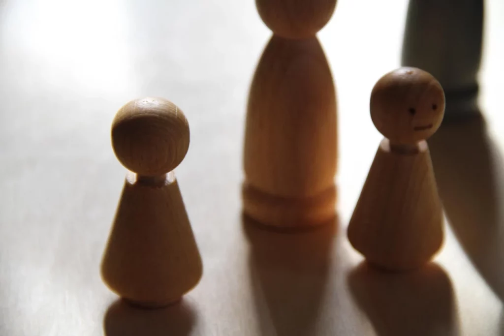 Houten poppetjes staan in een familieopstelling op een lichte tafel.